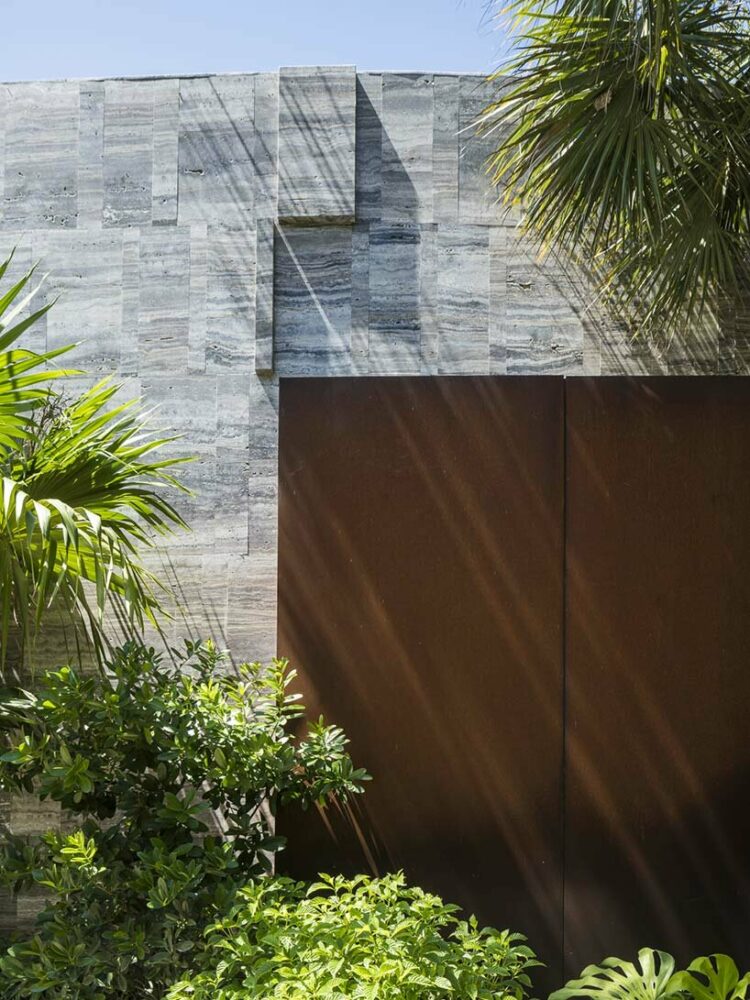 a corten steel gatehouse is overgrown by tropical nature in coconut grove, miami