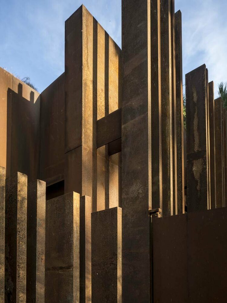 a corten steel gatehouse is overgrown by tropical nature in coconut grove, miami