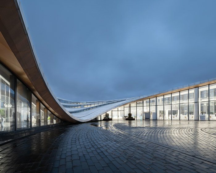 MUDA-architects' coastal haikou visitor center enclosed by a fluid, cascading rooftop