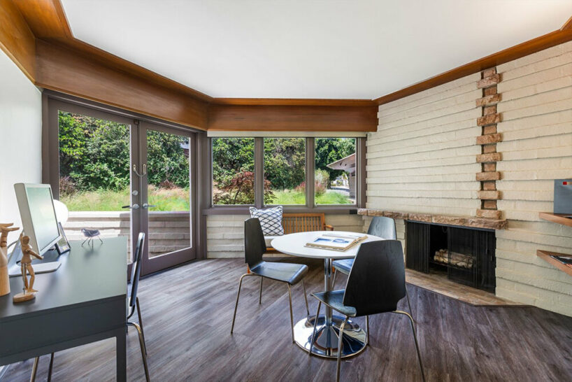 the hexagonal living room features an asymmetric fireplace and walls of glass that provide views of the garden
