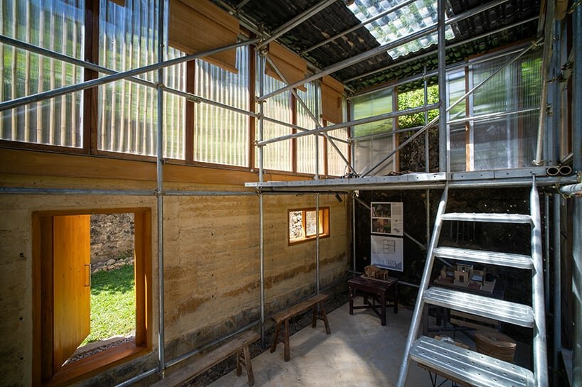 a metal scaffolding structure is leaning against the inner face of rammed earth wall