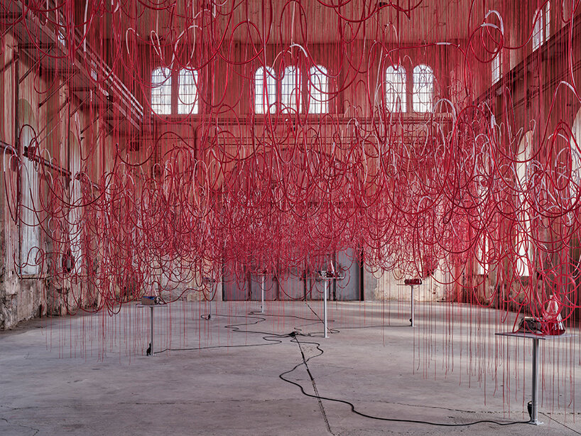 chiharu shiota's red intertwined tubes drift in former assembly hall in austria