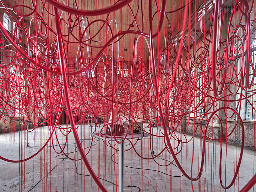 chiharu shiota's red intertwined tubes drift in former assembly hall in austria