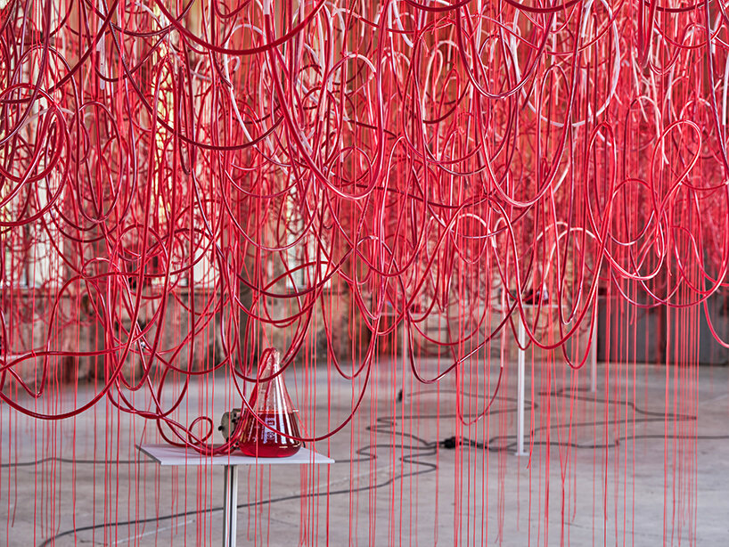 chiharu shiota's red intertwined tubes drift in former assembly hall in austria