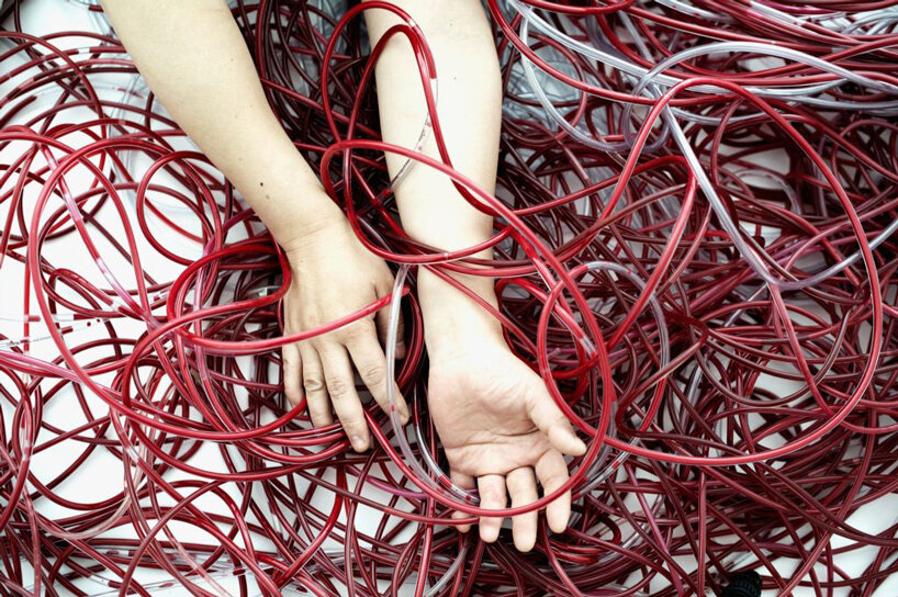 chiharu shiota's red intertwined tubes drift in former assembly hall in austria