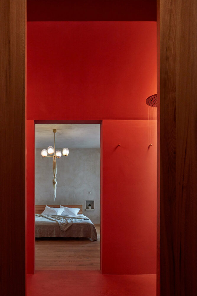 the bedroom with stucco walls and storage spaces connects to the bathroom with a curved ceiling