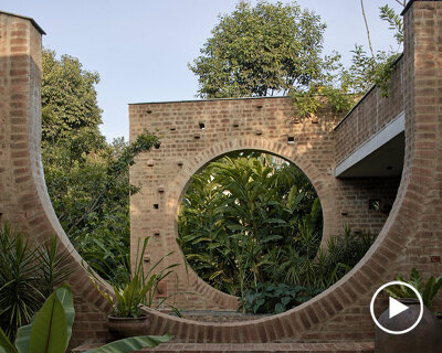 echoing ancient brick ruins, this public center in india peeps through a dense tropical flora
