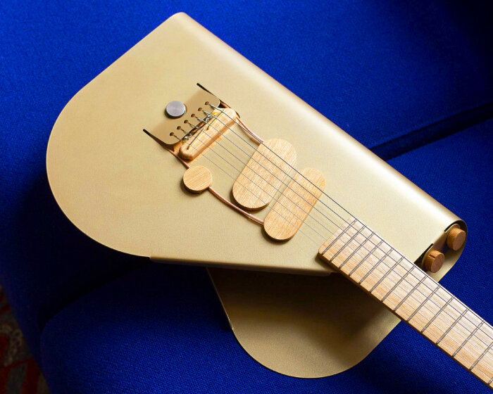 cosmo electric guitar wraps bent luminous metal sheet around its wooden instrument parts