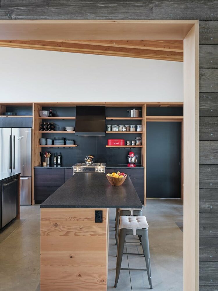 dark granite countertops and steel backsplash stand in contrast to lighter wood tones