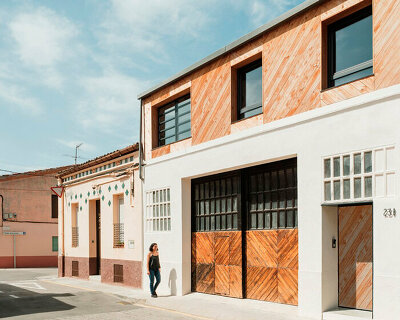 repurposed wood shapes up the roof and furniture of converted warehouse in spain