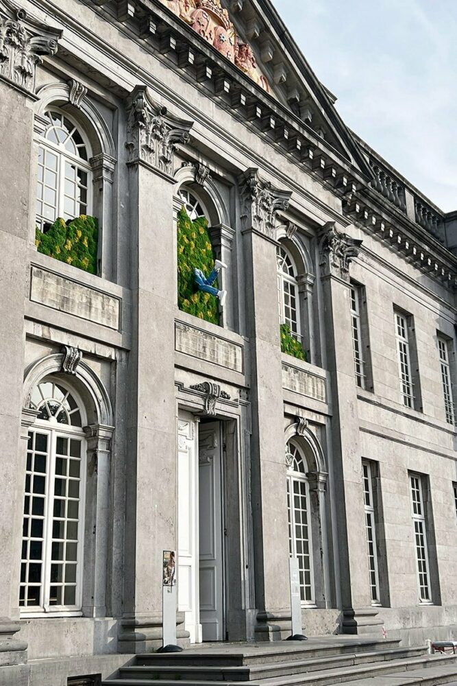 a character appears to dive into a wall of plant moss across the facade
