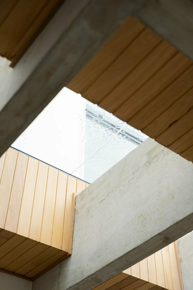 concrete beams meeting wooden ceilings give rise to eight skylights, illuminating the living and dining spaces