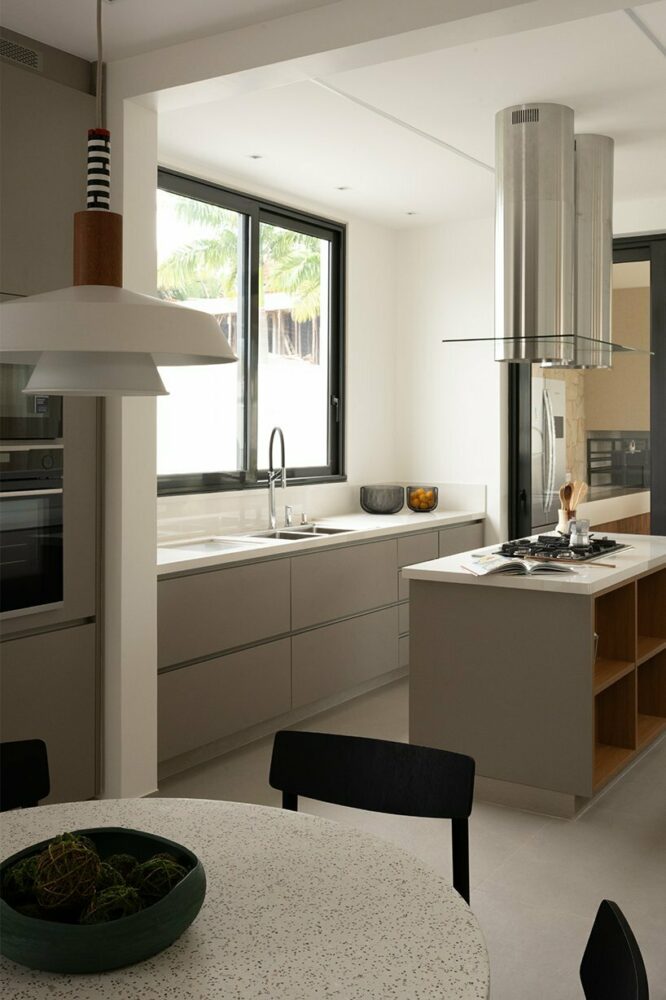 spacious white counters, a cooking island, and gray cabinets define the kitchen, connected to the dining room