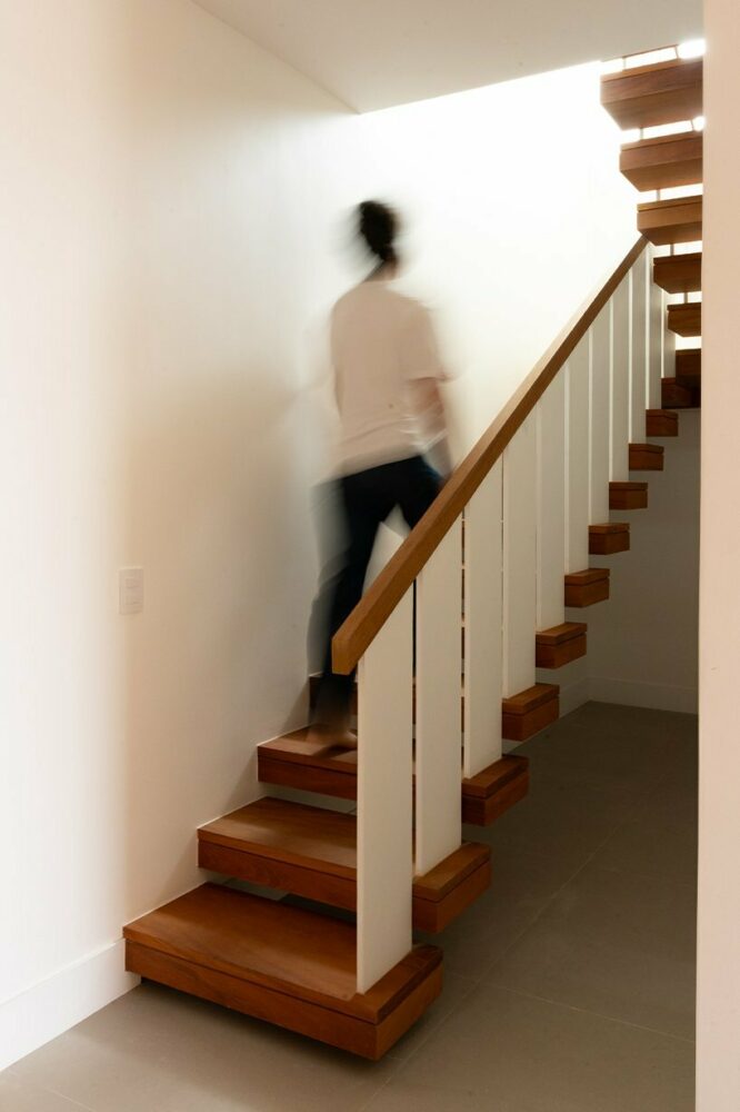 cantilevered wooden steps and sleek white railings enable natural light to illuminate the entrance hallway