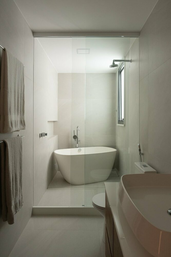 a monochrome master suite bathroom is marked by a freestanding bathtub