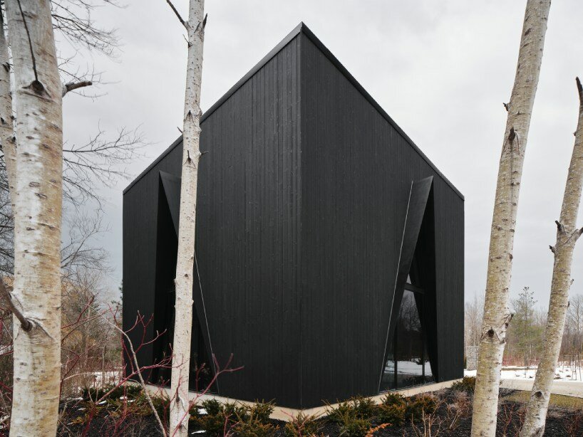 charred wood ski chalet by atelier RZLBD tucks into sloping terrain in rural canada