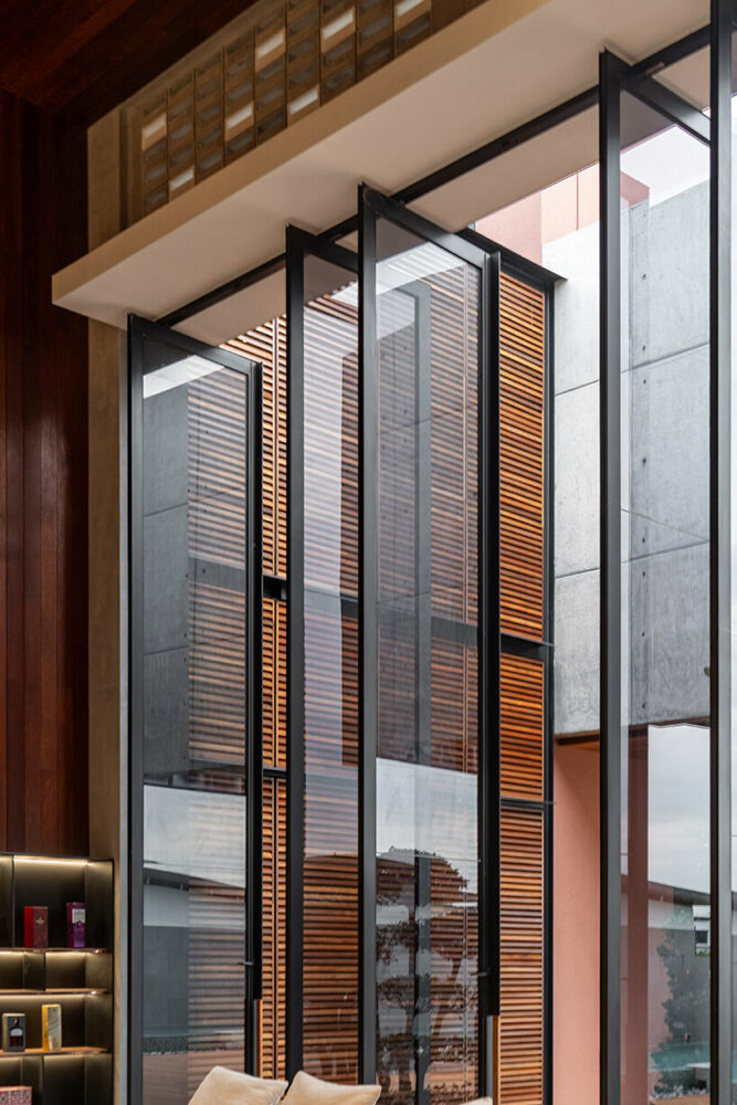 the tall pivot glass door vanishes when opened, seamlessly blending the external and internal spaces