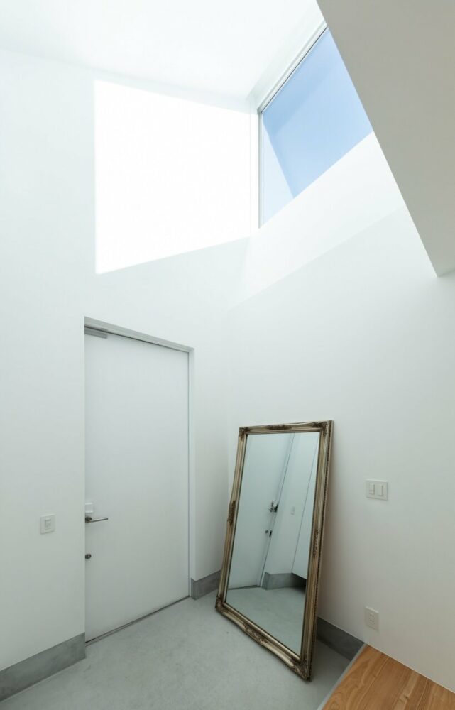 broad ash floors, pristine white walls, and sunlit surfaces characterize the interior