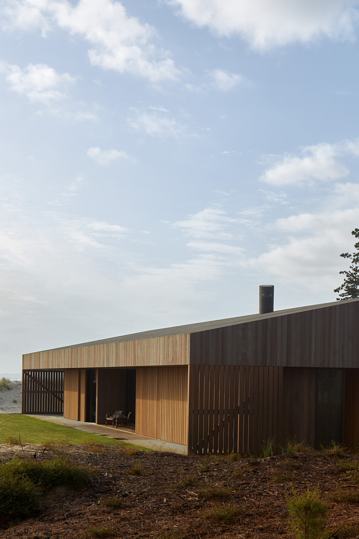 fearon hay's 'te arai' house frames dunes through timber shutters