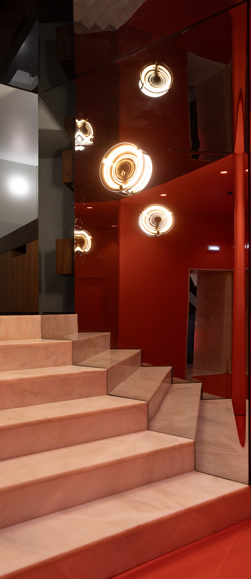  a red transition space with a marble staircase and mirrored walls offers a kaleidoscopic experience