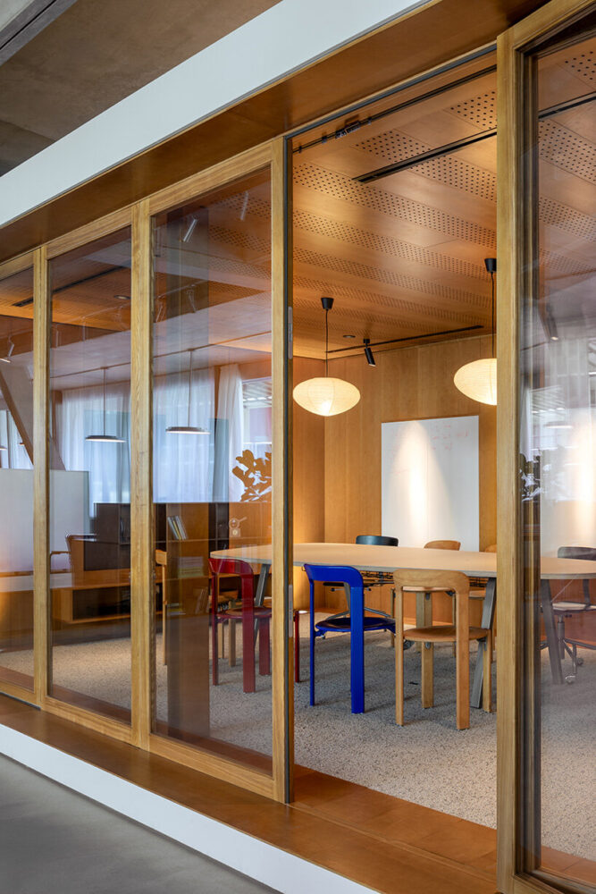 glass-enclosed functional spaces are separated by visible ceiling beams