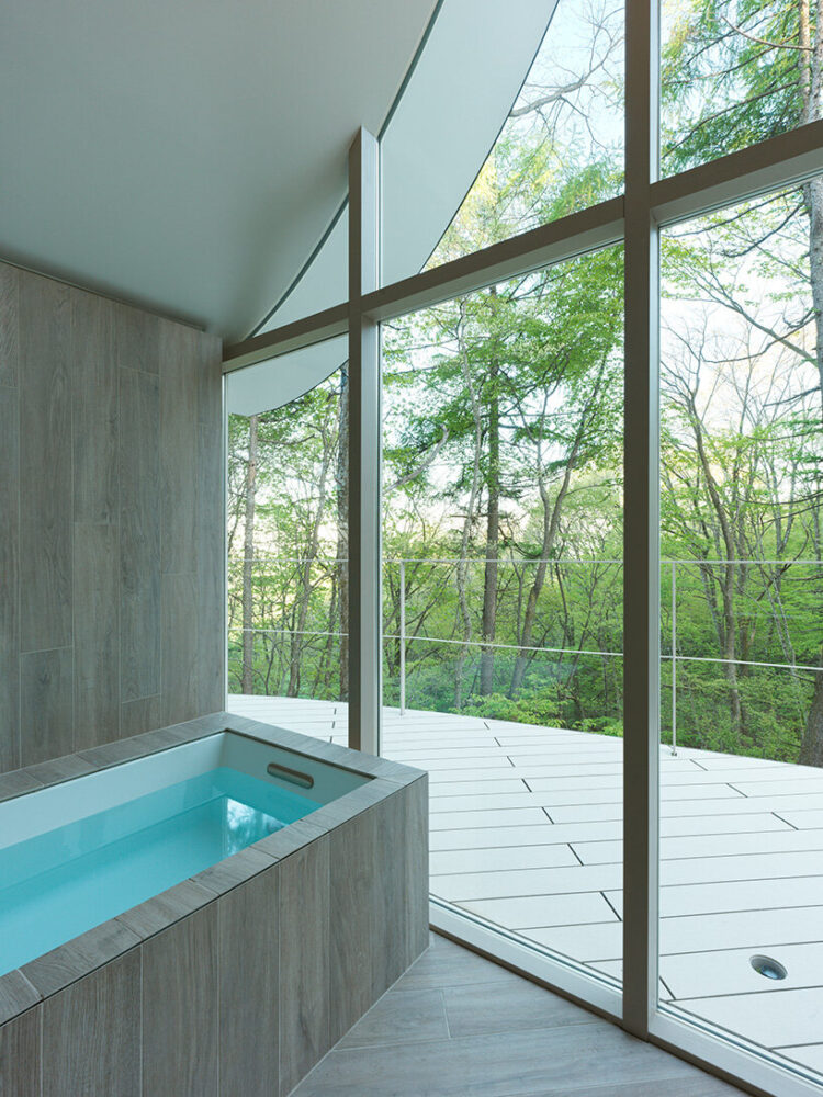 floor-to-ceiling openings offer forest views to the bathroom cottage