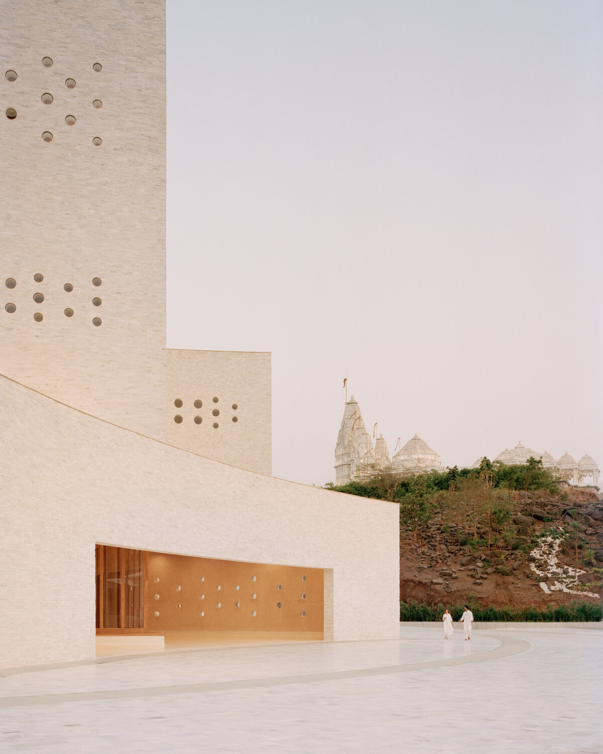 sequence of curved white marble volumes shape serie architects' ashram auditorium in india