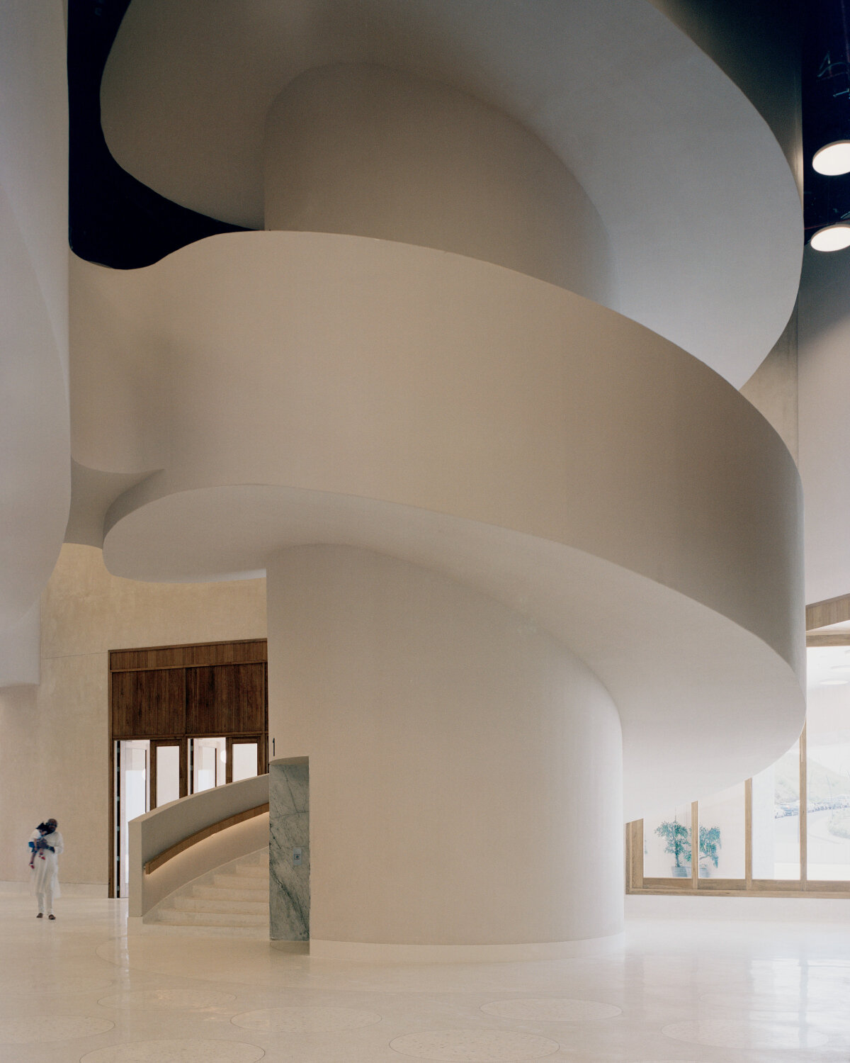 sequence of curved white marble volumes shape serie architects' ashram auditorium in india