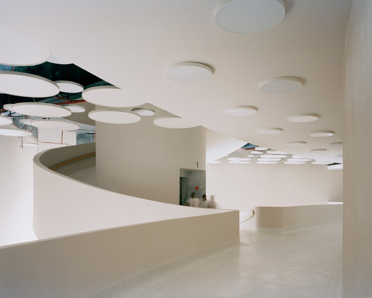 sequence of curved white marble volumes shape serie architects' ashram auditorium in india