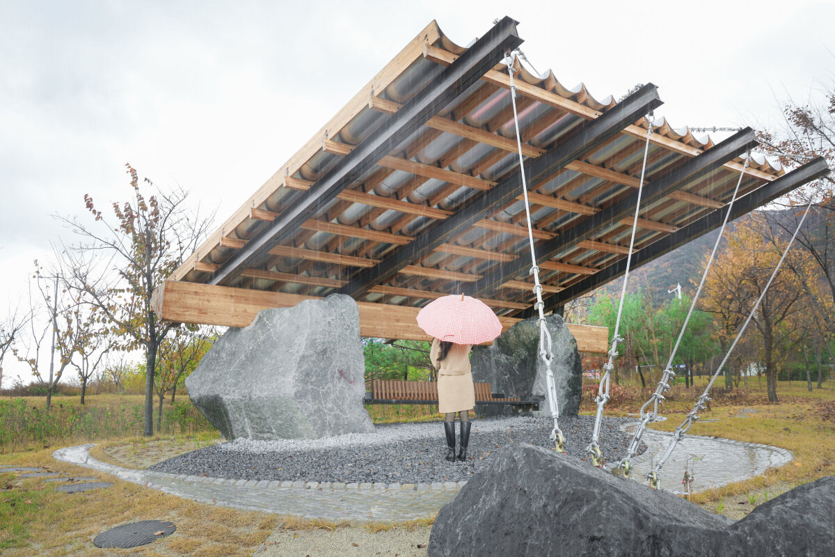 wood & metal canopy rests atop rocks for 'urban interior' installation in south korea