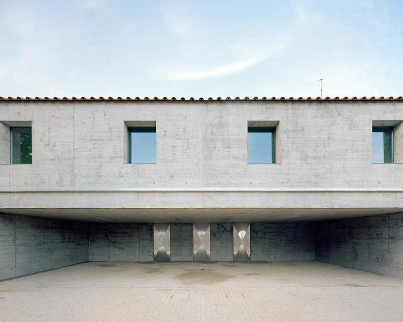 the dual-purpose concrete structure houses a garage and a residence under a single roof