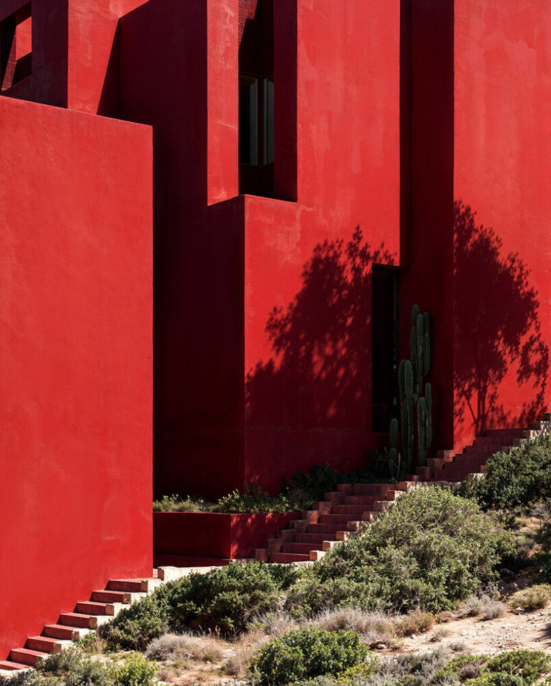 painted in a vivid earthy red, the resort contrasts with the greenery around