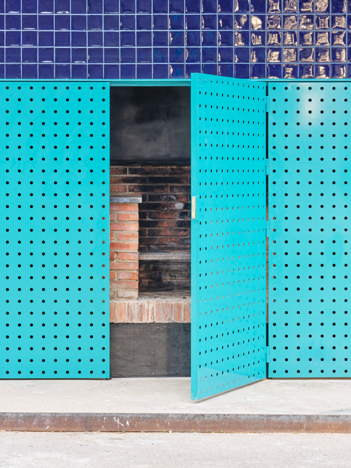 ceramic blue tiles evoking mediterranean hues clad h3o architects' public barbecue in spain