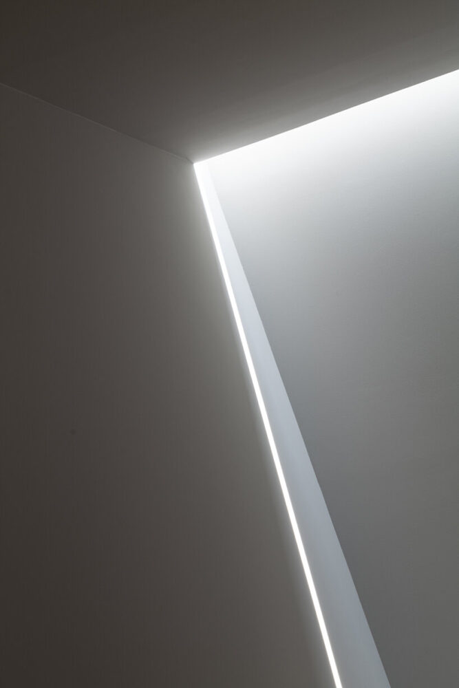 sharp beams of natural light enter through a house-shaped slit at the top