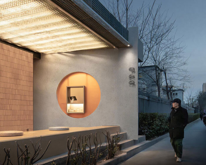 lantern-like lighting shines through suspended metal grid within tea pavilion in beijing