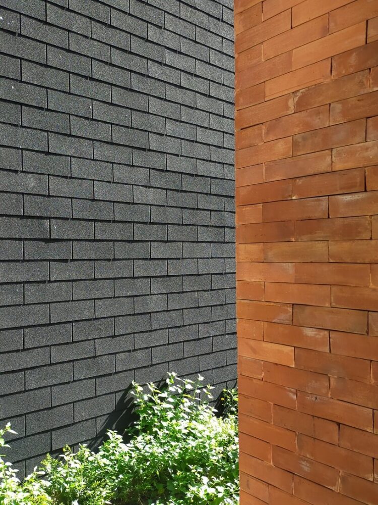 material contrast between black roof sheet and terracotta bricks