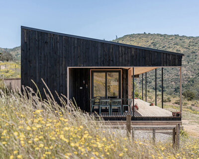 charred timber wraps linear casa las tupas, topped with pitched roof in northern chile