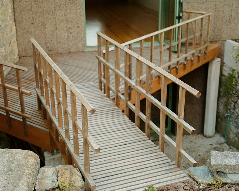 a light wooden terrace connects the interior to the garden