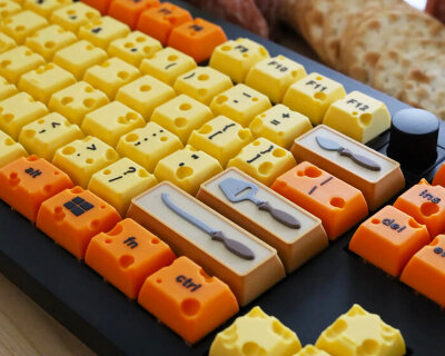swiss cheese mechanical keyboard types with caps shaped like grater, knives and jar of jam