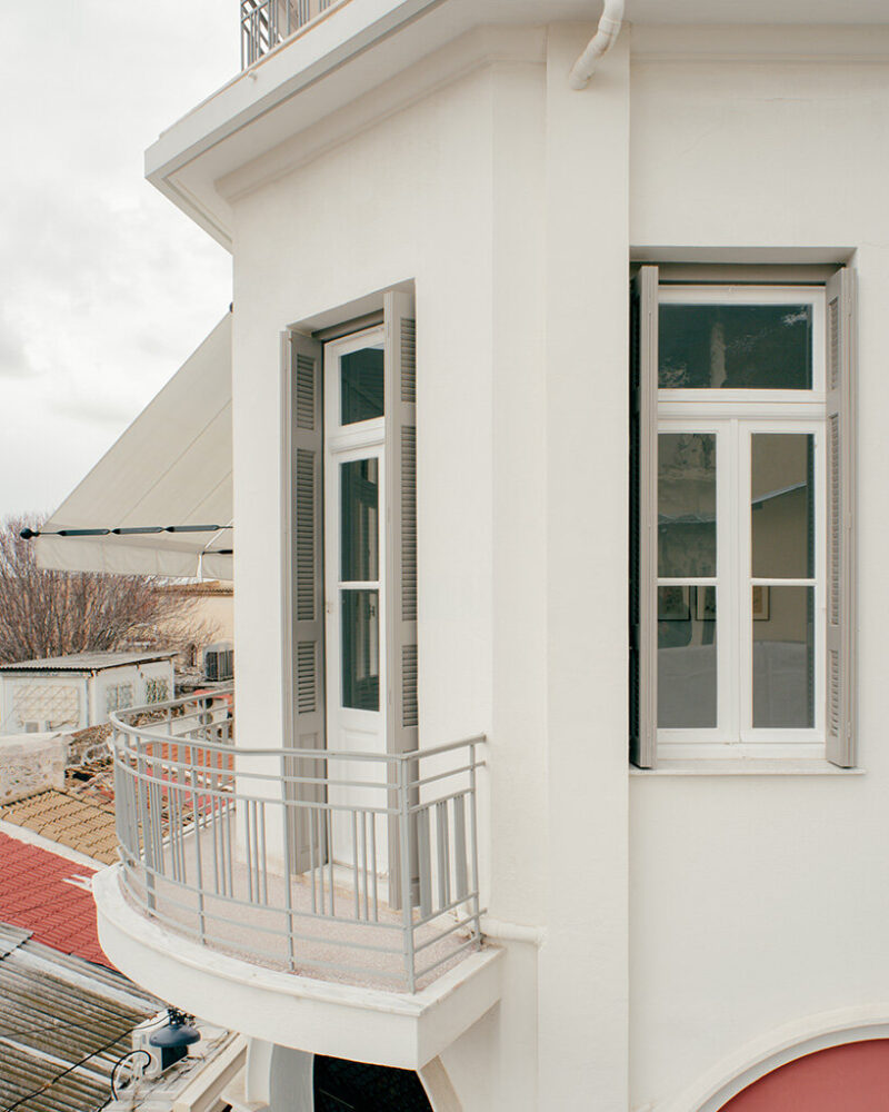 long gridded windows with grey shutters open toward the Acropolis