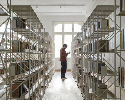 suspended steel shelving forms permeable curtain within revitalized historic slovak library