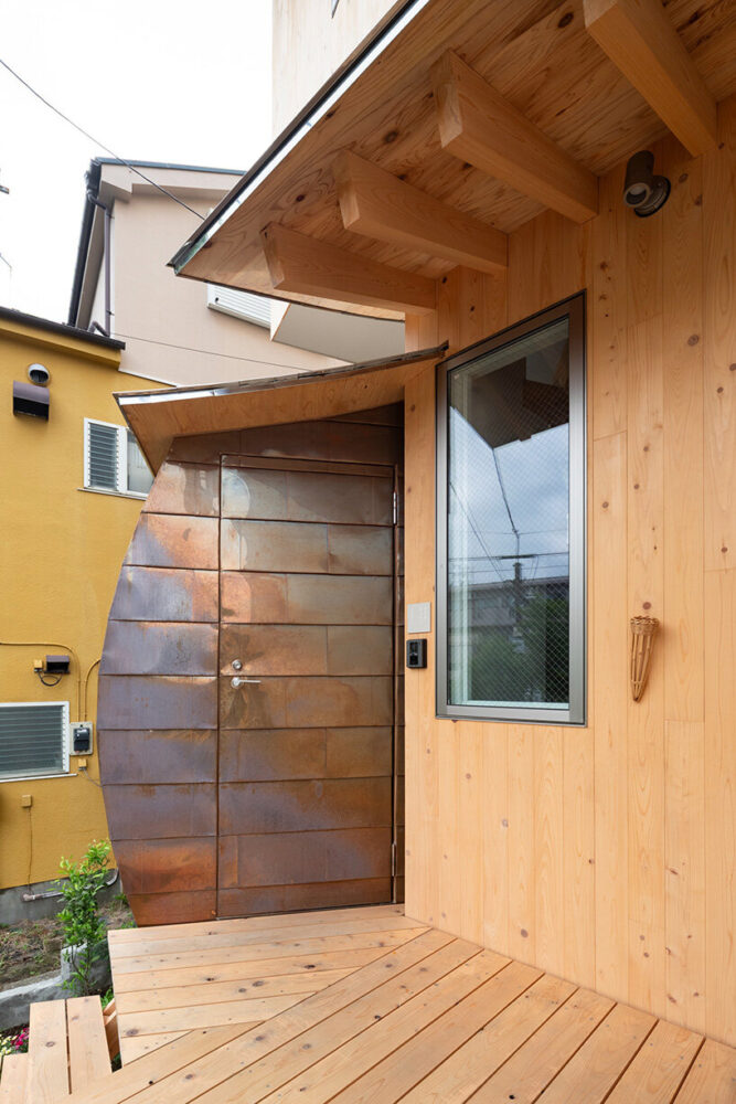 the entrance combines warm timber and patinated copper panels