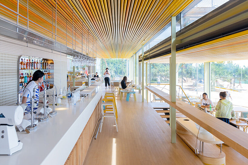 the soft hues of the aluminum sunshades and the movement of people within betray the presence of the café