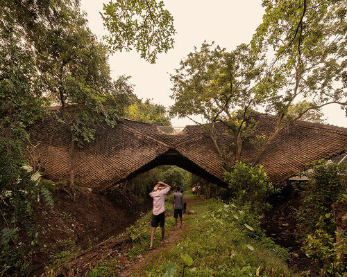 wallmakers wraps its suspended ‘bridge house’ in skin of thatched scales