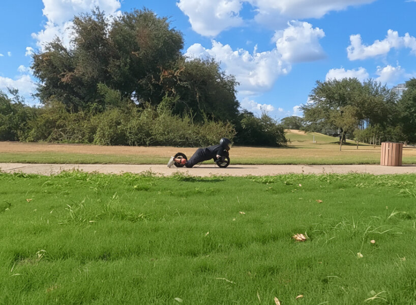 the creator attaches the wheel directly to his legs using painter’s stilt straps as braces