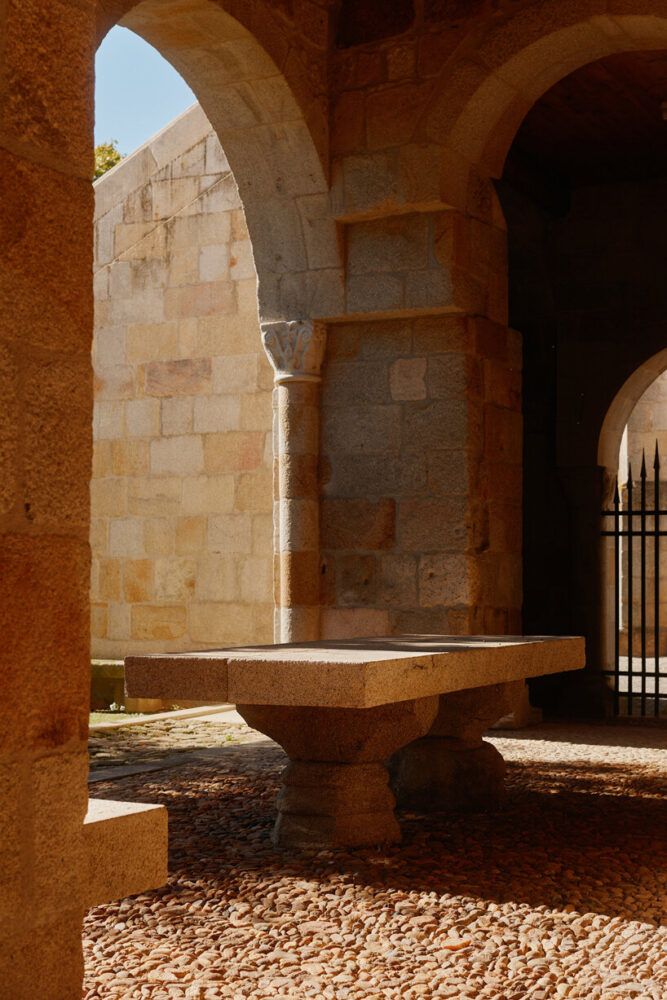 a stone table and columns sit under the arches of the historic monastery