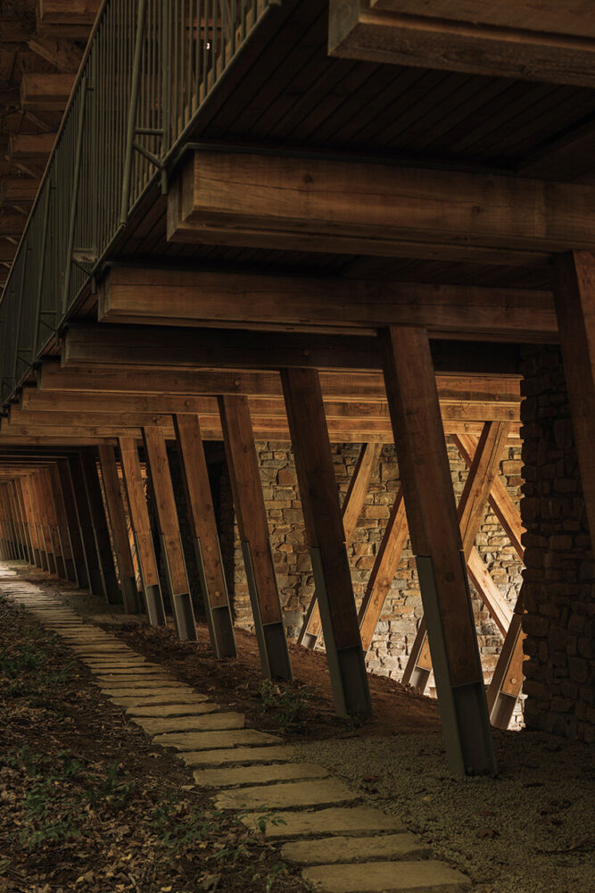 the wooden structure rises above the stone base on slender pilotis