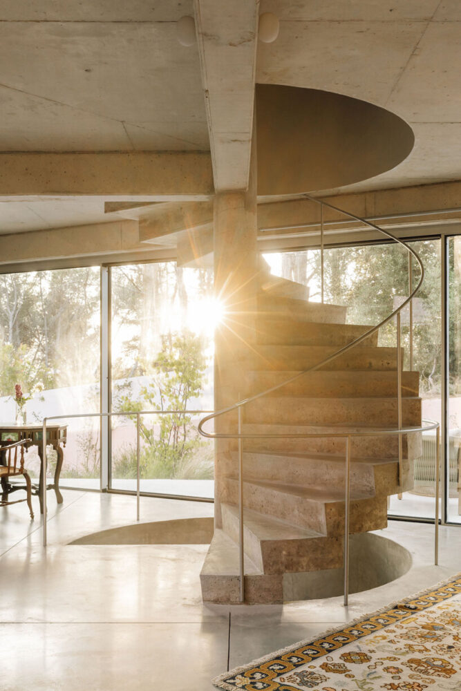 structural elements such as exposed beams and the staircase subtly articulate different areas