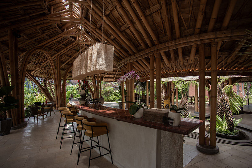 the bar and dining areas unfold beneath the exposed bamboo roof structure