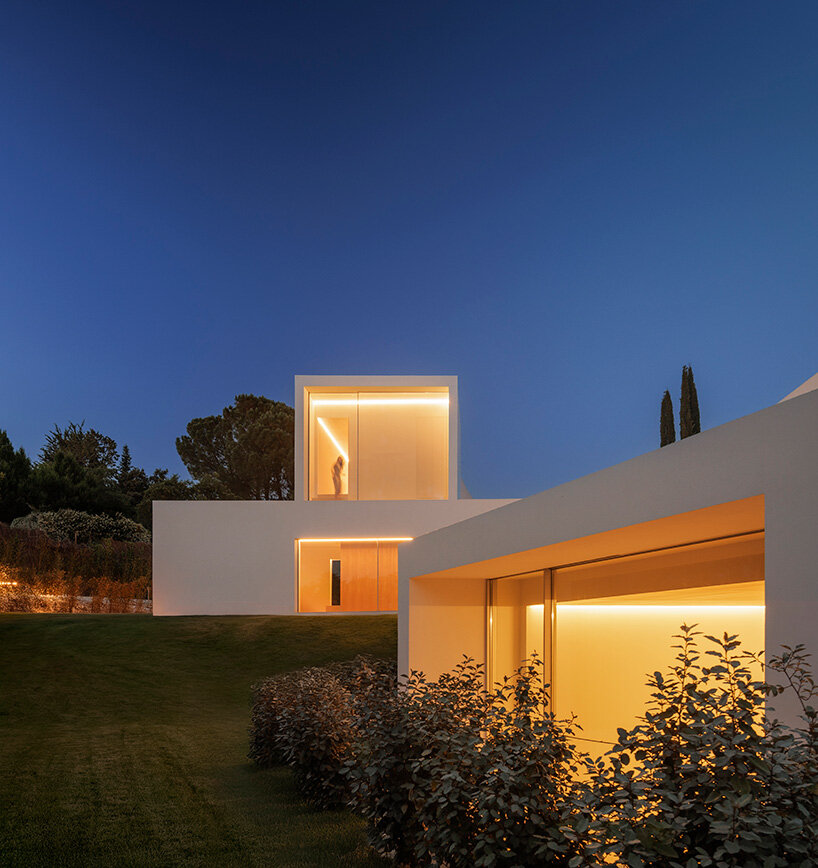 warm interior light reveals the stepped volumes as they settle into the sloping garden